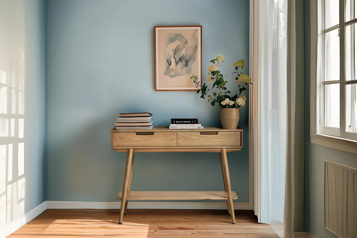 Wooden console table with books and a vase against a blue wall