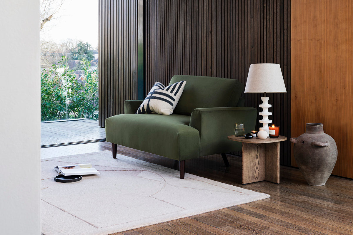 Model 05 Loveseat in Vine velvet beside a side table and lamp